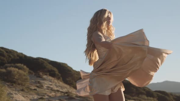 Dancing Young Blond Woman In Gold Dress