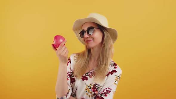 Medium Studio Shot on an Orange Background of an Elegant Young Caucasian Blonde Woman Holding a Red