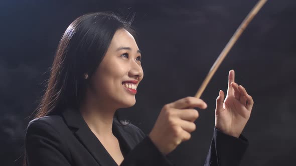 Close Up Of Asian Conductor Woman Holding A Baton And Showing Gesture Quickly In The Black Studio