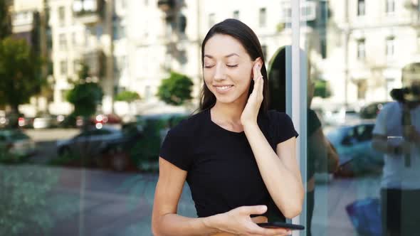 Portrait of a Young Brunette Woman with Headphones While Walking