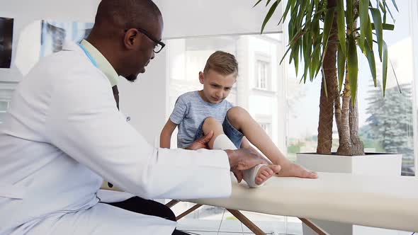 Male Doctor Checking Bandage on the Leg of Cute Boy