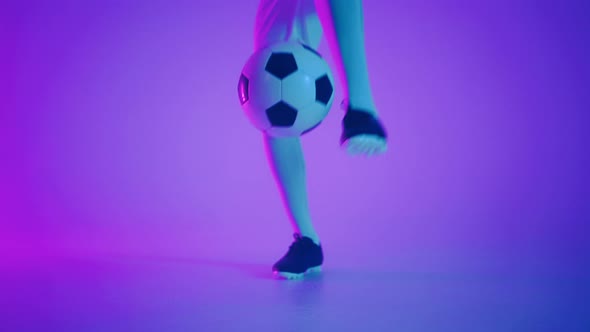 Black Man a Player Juggles Football Ball in a Dark Studio with Neon Lights on the Floor and Red and