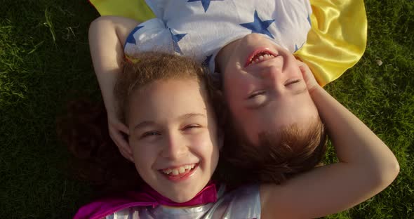 Children Superheroes Little Girl and a Baby Boy Lie on the Grass in Superhero Costumes