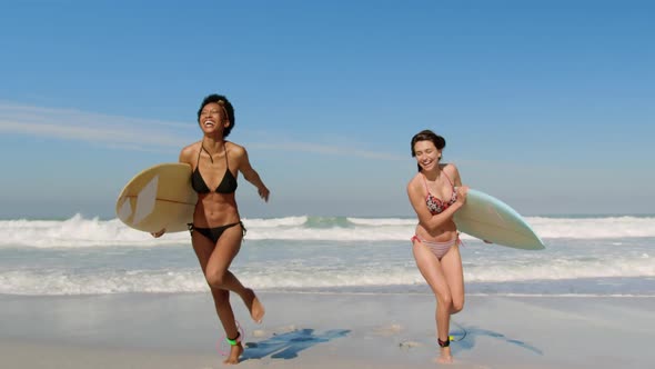 Young female friends running with surfboard 4k