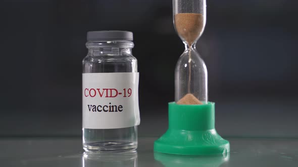 Hourglass and Bottle of Coronavirus Infection Covid19 Vaccine