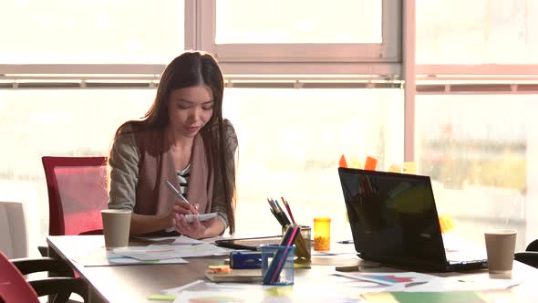 Smiling Girl Rewriting Info From Tablet in Notebook.