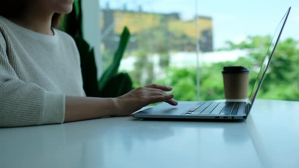 Closeup a woman working and touching on laptop computer touchpad on the table