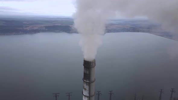 Aerial view of high chimney pipes with grey smoke from coal power plant. Production of electricity