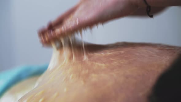 Manual Therapist Does Massage Procedure with Honey to Woman
