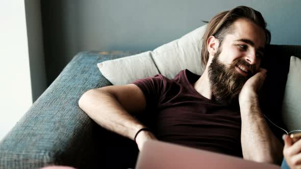 Couple kissing while listening music on mobile phone in living room 