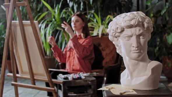 Artist in an Art Studio with Plants Young Pretty Woman Takes a Photo of Her Painting Greek Head