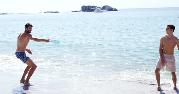 Friends playing frisbee at beach