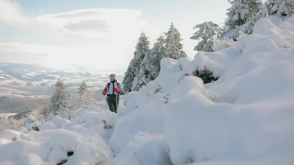 A Young Woman is Slowly Climbing to the Top of a Snowcapped Mountain