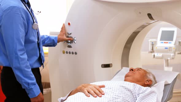 A patient is loaded into an mri machine while doctor and nurse watching