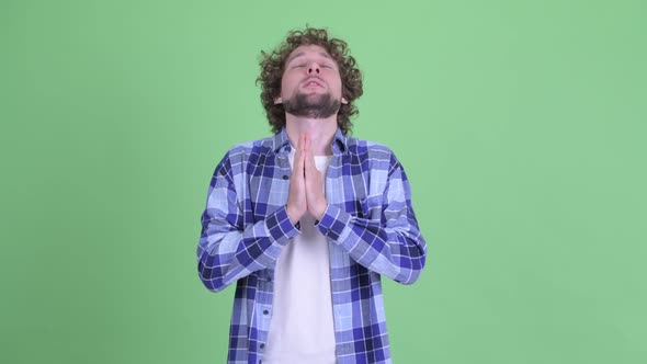 Young Bearded Hipster Man Looking Desperate While Praying