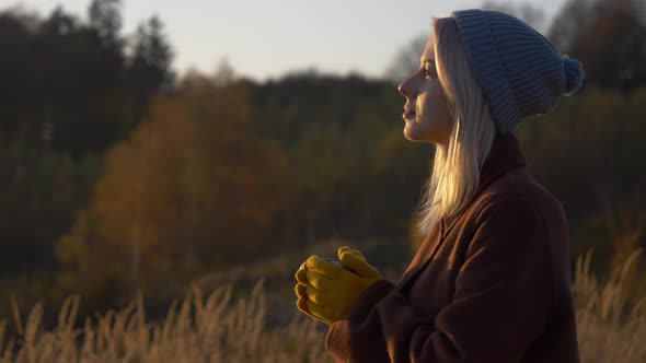 Beautiful girl with mug of tea in mountains Sudety in November in sunset