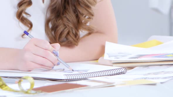 Fashion Designer Draws Sketches for a New Collection in Her Workshop. Close Up