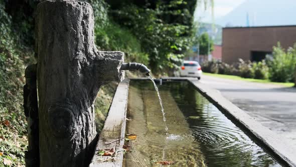 Mountain Water Pours From a Tap Into a Wooden Container on Liechtenstein Street