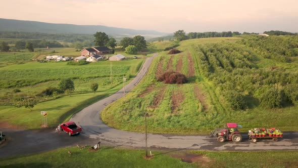 Aerial view of following tractor down country road in the rolling hills of West Virginia.