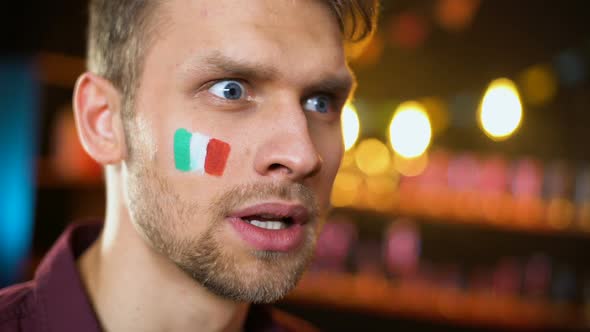 Cheerful Italian Fan With Flag Painted on Cheek Shouting, Team Scoring Goal