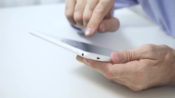 Closeup of an Elderly Man's Old Hands Using a Tablet