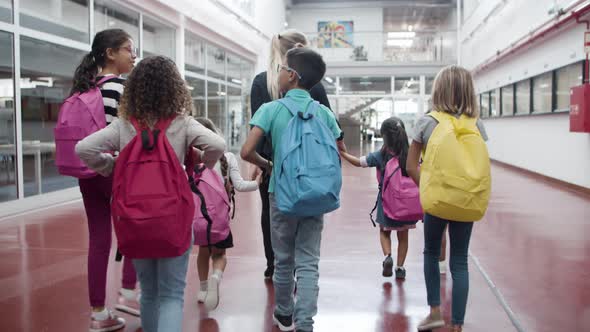 Multiethnic Kids Walking Along Corridor with Female Teacher