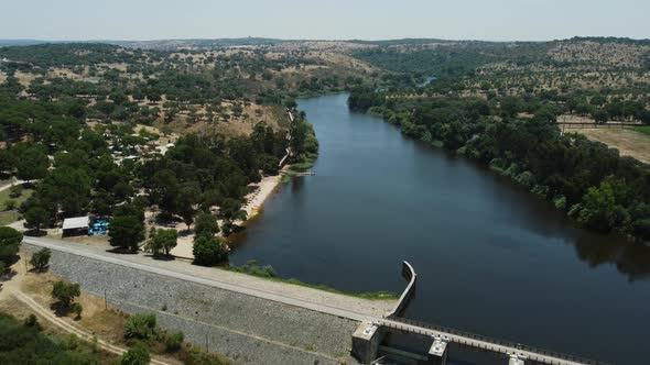 Aerial backwards shot of dam and bridge over Portuguese river in Alentejo,Portugal during beautiful