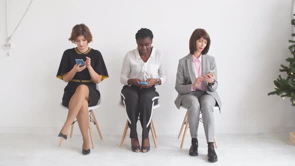 Three Business Girls Expect Interviews Sitting on Chairs in the Hallway of an Office Building