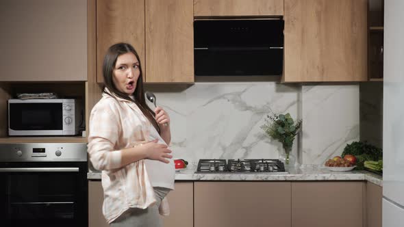 Pregnant Woman Sings with Spoon Imitating Microphone Dances