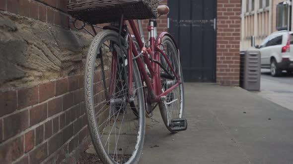 Red bicycle with basket parked against a brick wall in city centre of Cambridge, England.