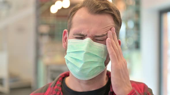 Portrait of Young Man with Face Mask Having Headache