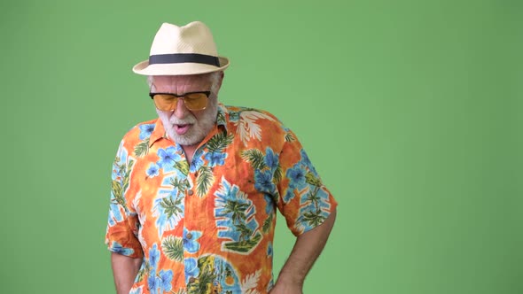 Handsome Senior Bearded Tourist Man Ready for Vacation Against Green Background