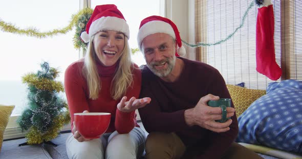 Happy caucasian mature couple making video call in room full of christmas decorations