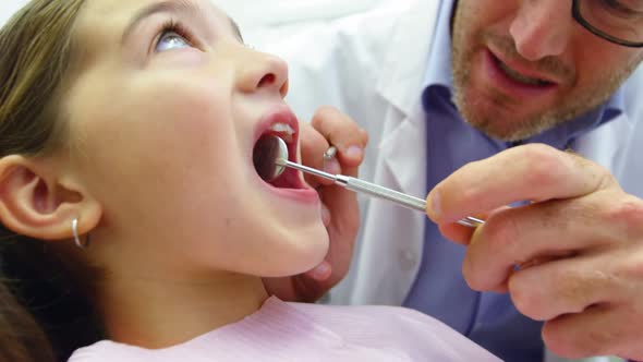 Dentist examining a young patient with dental tools