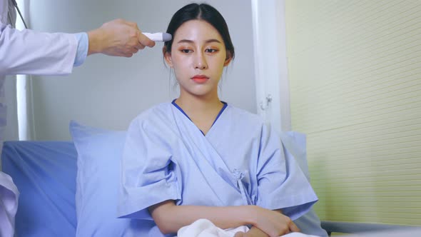 Asian Female Patient in Uniform Being Measured By Tympanic Thermometer for Temperature in Hospital