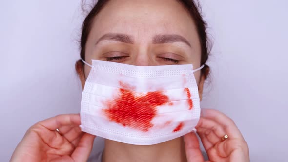 Exhausted Sick Woman with Brown Eyes Puts on Bloody Mask