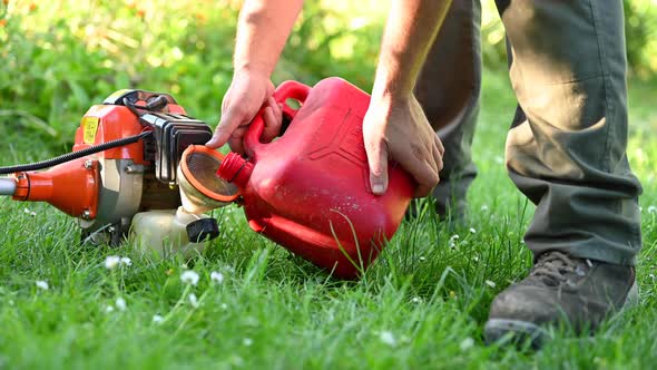 Gardener Refueling Brush Cutter Close Up. Gardening Tools Maintenance. Lawn Care with Brush Cutters.