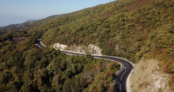 Aerial View of Car Driving Along The Winding Mountain Pass Road Through The Forest Trees. Autumn