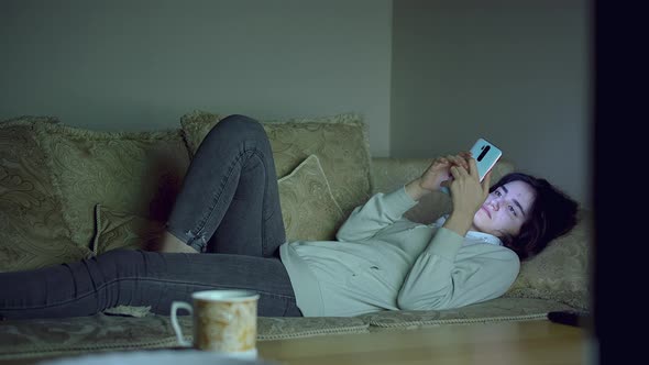 Girl Night Lies on the Couch with a Mobile Phone in Her Hands Can Not Sleep