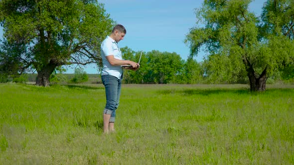 Businessman Works Behind a Laptop on the Lawn