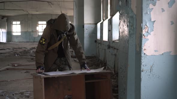 A Soldier or Stalker in a Gas Mask is Looking at a Map or Diagram of a Building