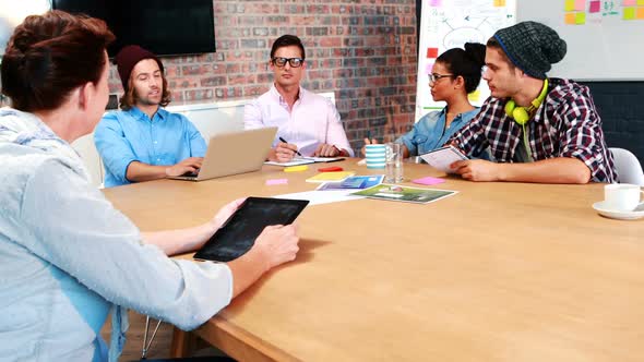 Businesspeople interacting while using laptop