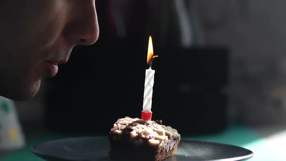 Close-up of Face of Man Blowing Out One Candle on Little Cake.