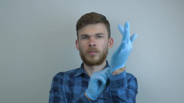 Guy puts on latex medical gloves for virus infection prevention and protection.