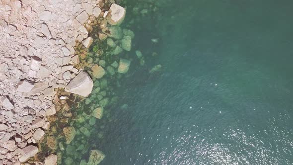 Overhead view with rotation of clear ocean water and rocks on the shore in Torquay, England.