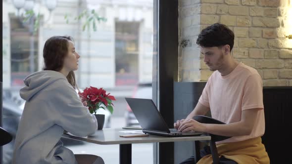Bored Caucasian Girlfriend Sitting with Absorbed Boyfriend Surfing Internet on Laptop