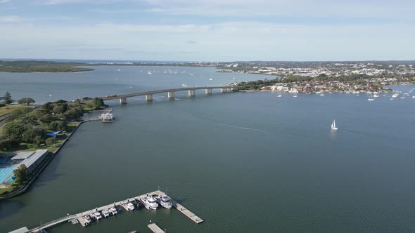 Aerial orbit shot of cross ocean bridge featuring parked boats, marina, sailboats, yacht and luxury