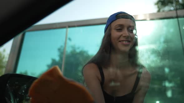 Front View Young Woman Rubbing Side Window Glass of Car in Slow Motion Smiling