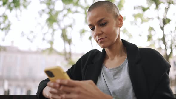 Happy bald woman texting on phone