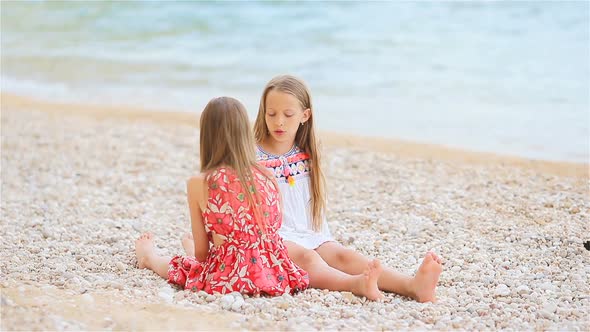 Two Little Happy Girls Have a Lot of Fun at Tropical Beach Playing Together